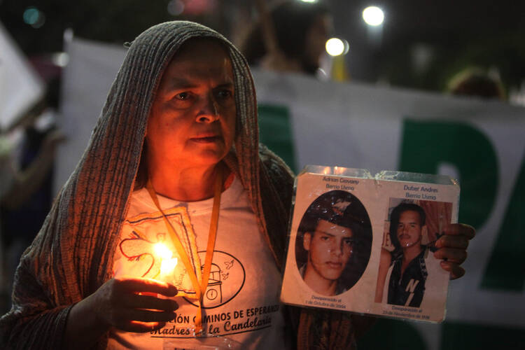 A woman holding a candle and images of disappeared victims takes part in a rally for peace Oct. 7 in Medellin, Colombia. Colombia's Catholic bishops urged the government and armed rebels to commit to an indefinite cease-fire while a new peace deal is negotiated. (CNS photo/Luis Eduardo Noriega A., EPA)