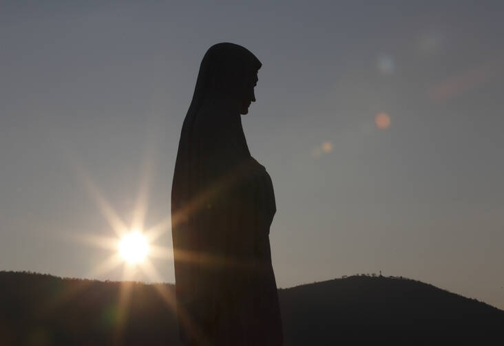 The sun sets behind a statue of Mary on Apparition Hill in Medjugorje, Bosnia-Herzegovina, in this 2011 file photo. (CNS photo/Paul Haring)