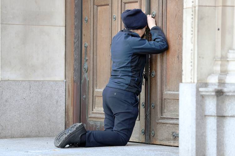 A woman prays at the closed doors of London's Westminster Cathedral in early April 2020 during England’s lockdown in response to the Covid-19 pandemic.