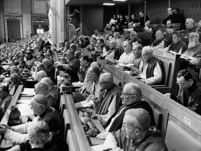 A black and white photo of priests and laymen sitting in St. Peter's Basilica