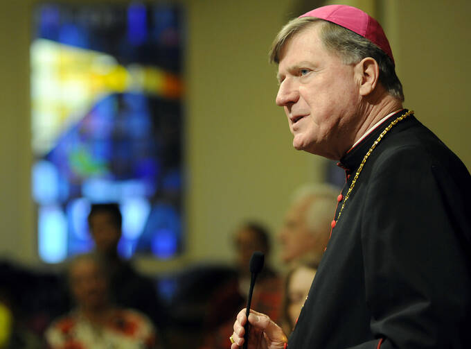 A man wearing a cardinals cap speaks into a microphone