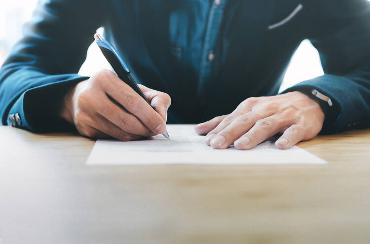 man writing with pen on a piece of paper