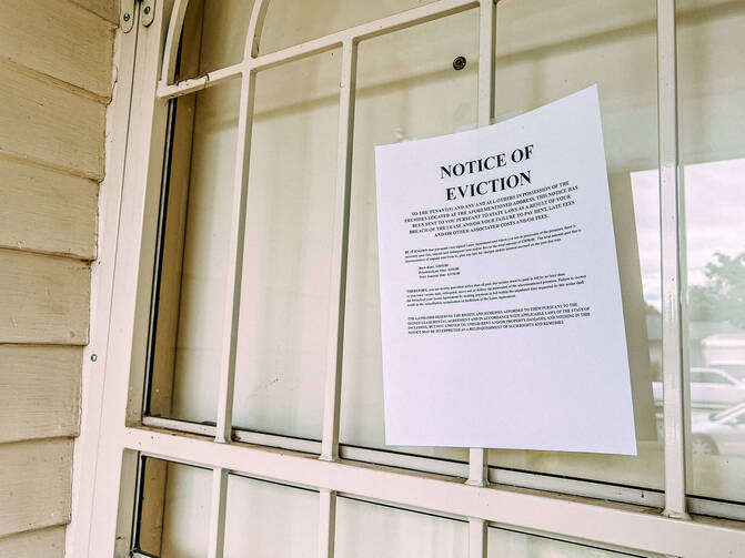 An eviction notice is taped to an iron gate in front of a white door with a peephole. (iStock/Jeremy Poland)