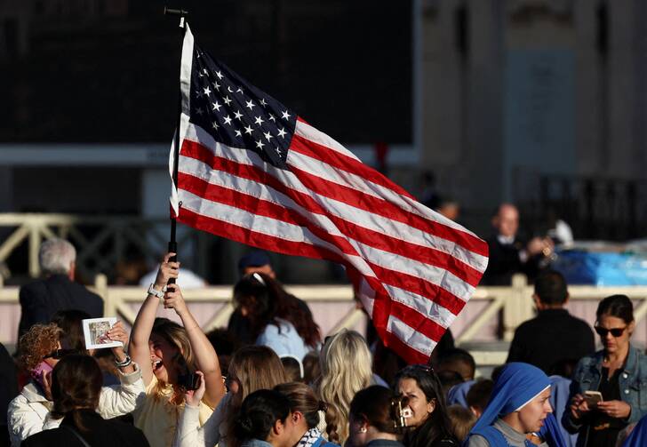 A woman holds an American flag as people gather ahead of the inauguration Mass for Pope Leo XIV at the Vatican on May 18. (OSV News photo/Yara Nardi, Reuters)