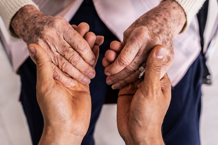 A close-up of a young person holding an older person’s hands 