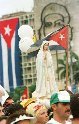 A statue of Mary is held above the crowd attending an outdoor Mass with Pope John Paul II during his 1998 visit to Cuba.