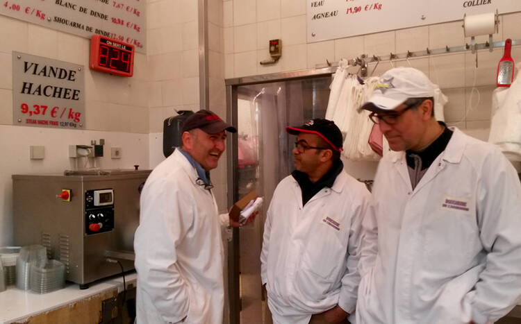 Philippe Zribi, far left, jokes with butchers Mostafa Makhoukh, center, and Abdel Haq at Boucherie de l’Argonne butcher’s store in Paris. Religion News Service photo by Elizabeth Bryant